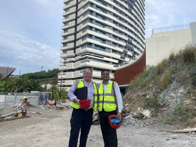 two men wearing hi vis jackets standing in front of a tall building