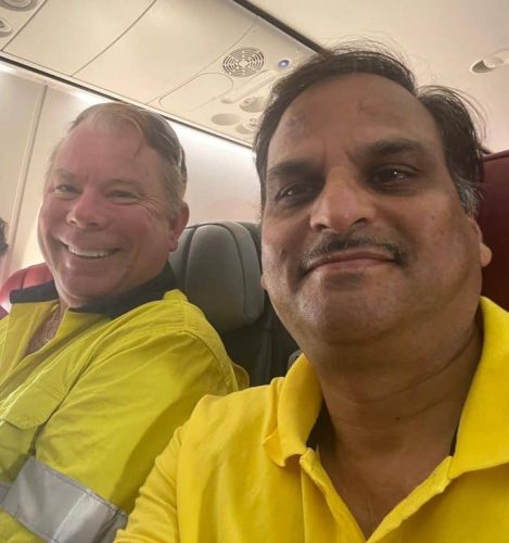two men happily sitting together and smiling on a plane